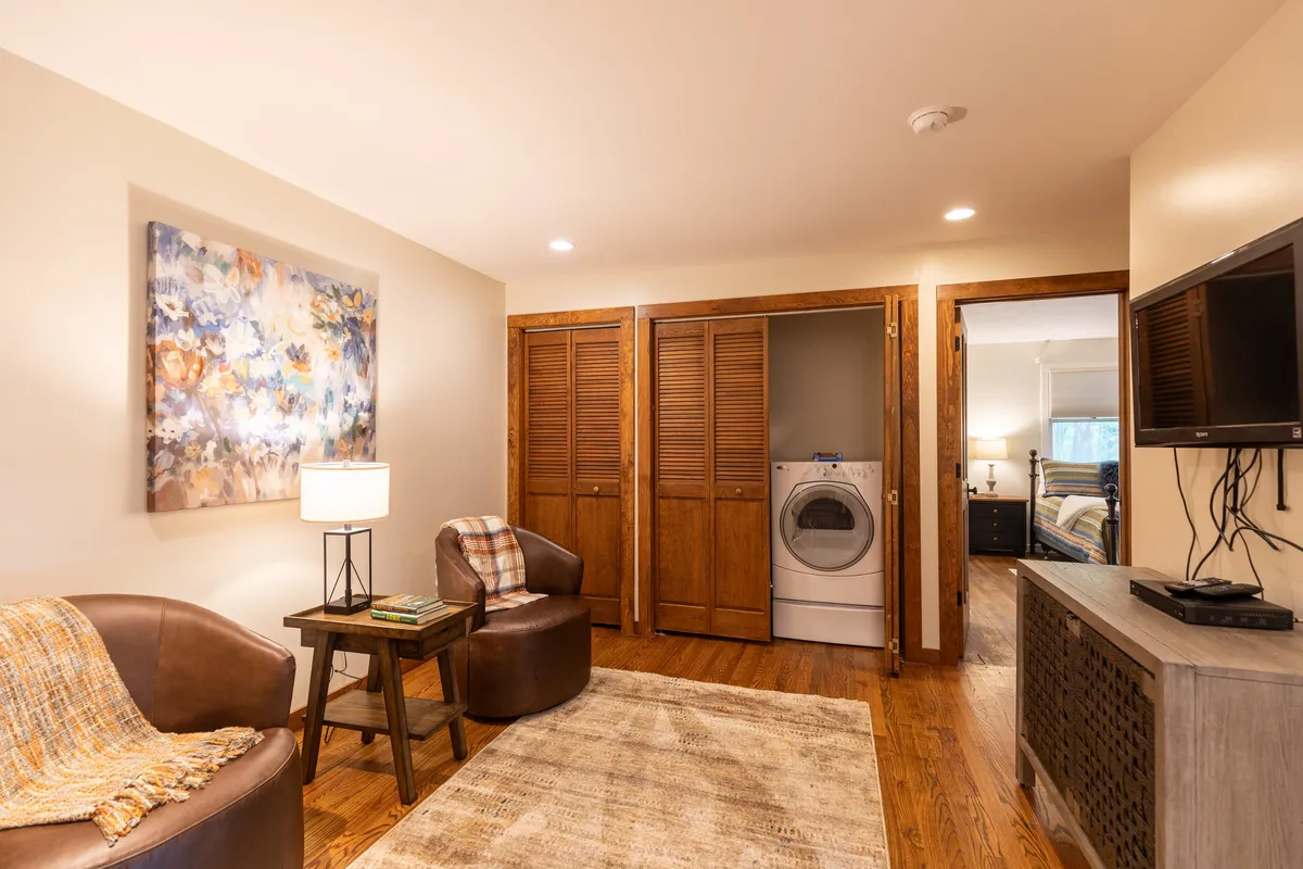A cozy nook with a small seating area, television, wall art, and a functional layout, suggesting a quiet retreat for watching TV, reading, or relaxing away from the main living spaces.