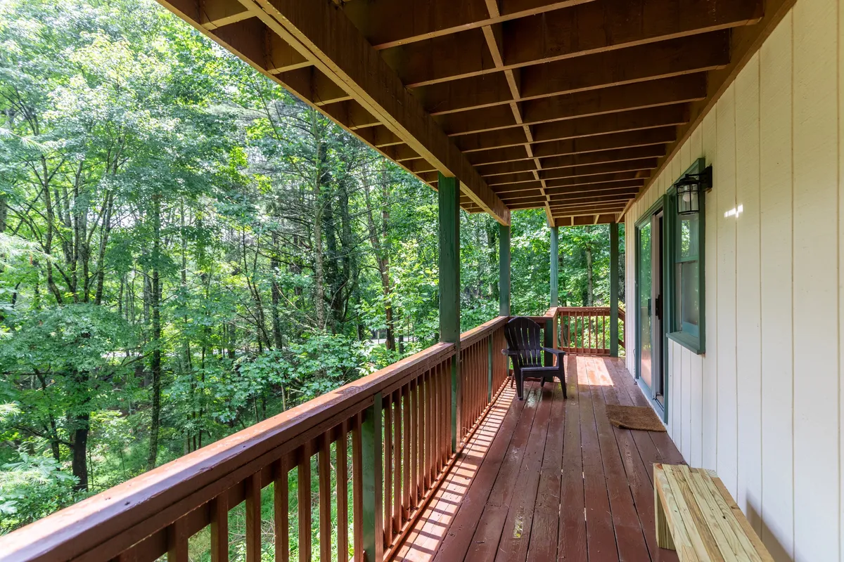 A single chair rests on a wooden deck encircled by greenery, creating an intimate spot for morning coffee, reading, or quiet contemplation. The lighting suggests a time of day ideal for watching sunsets or stargazing, aligning with the section’s mention of such activities.