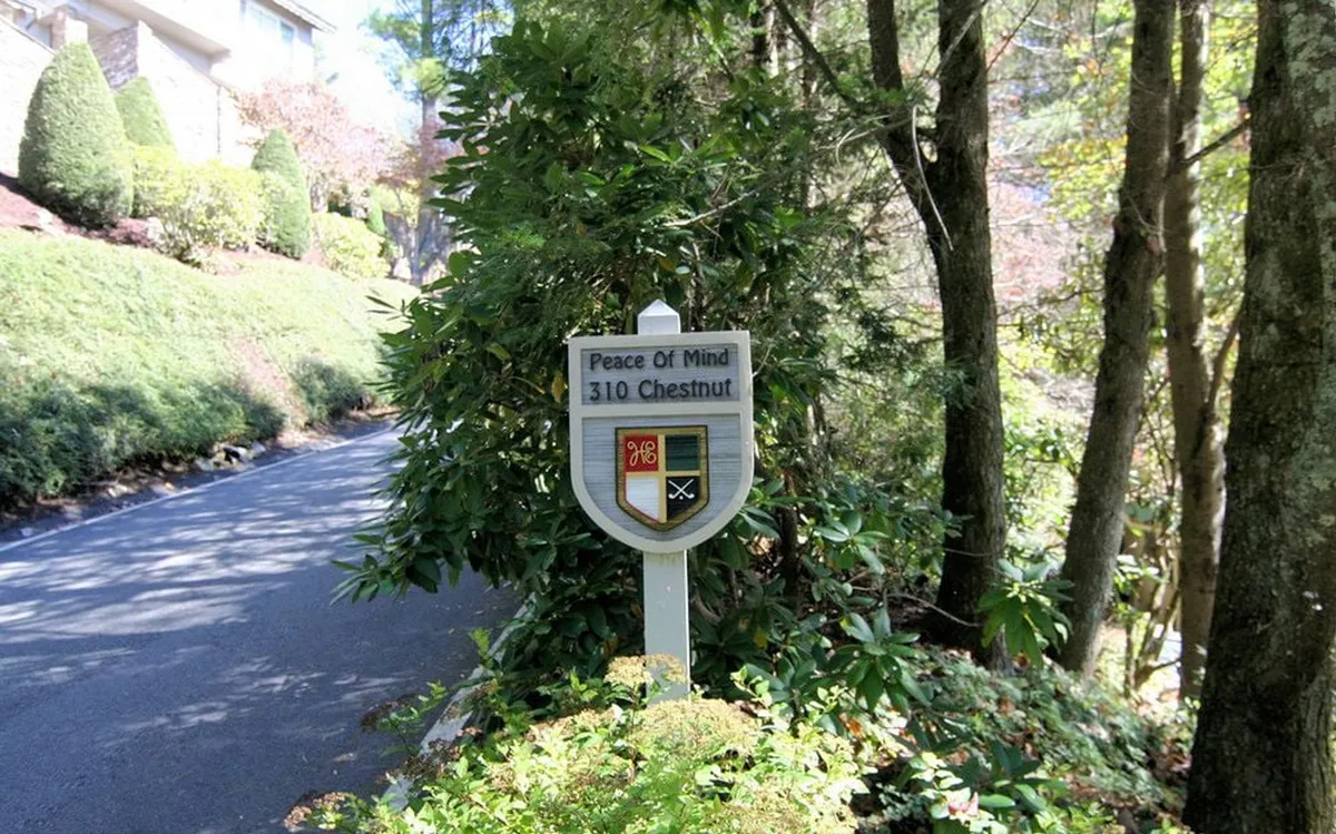 A roadside sign reading 'Peace Of Mind' at 310 Chestnut is surrounded by lush greenery and a quiet road leading into the property, setting the stage for arrival and exploration.