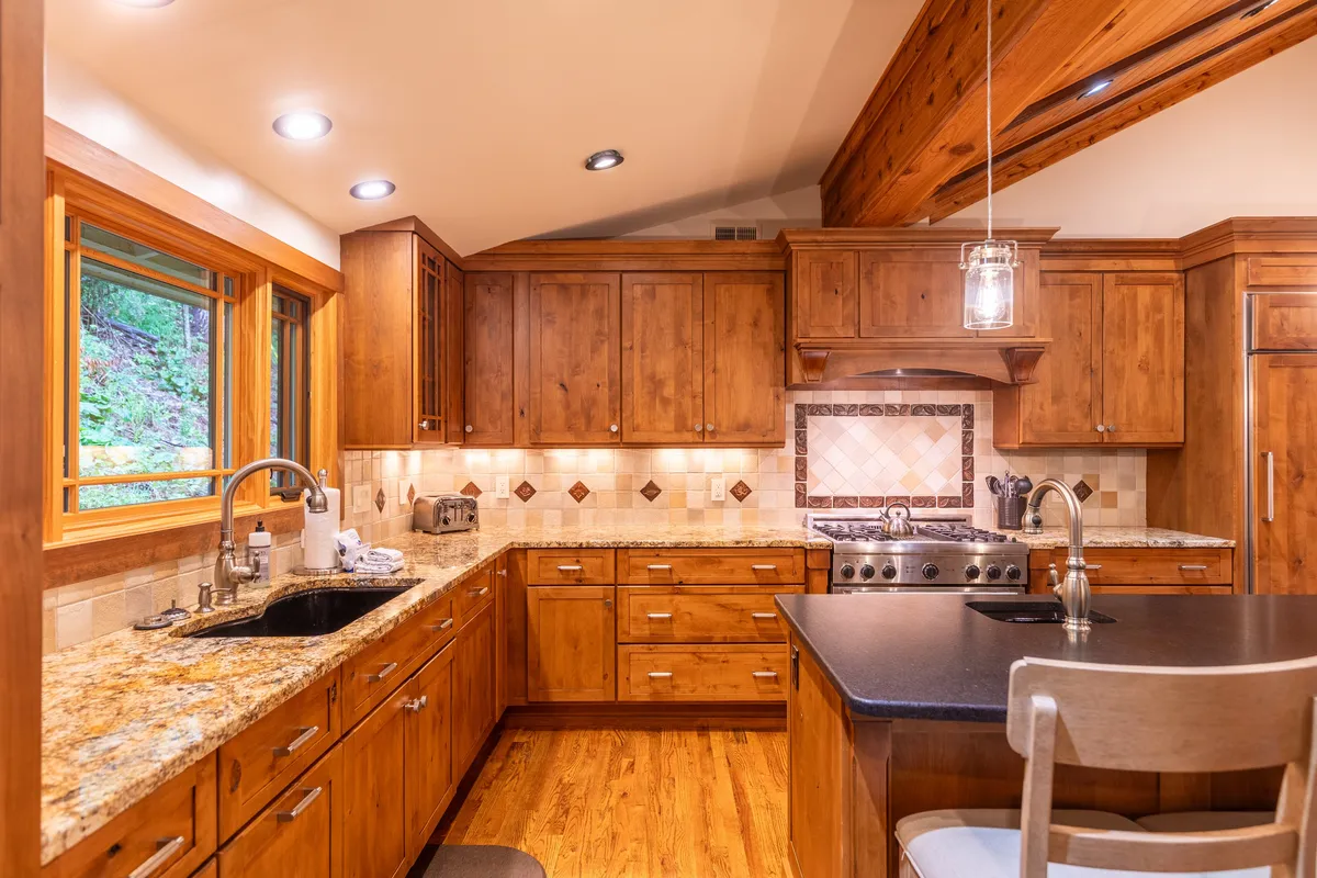 A cozy kitchen scene features expansive granite countertops, beautiful wooden cabinets, high-end stainless steel appliances, and a spacious kitchen island under natural light. Family members or friends are seen gathered around, possibly baking or preparing a festive meal together.
